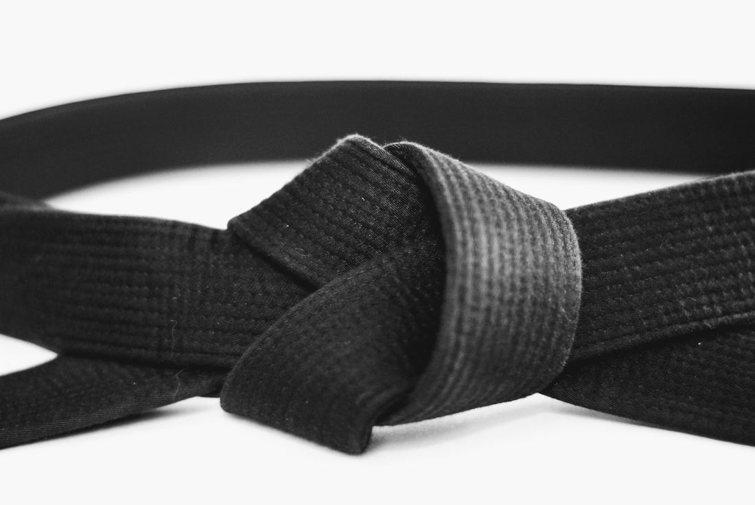 A black belt tied around the waist of a white uniform