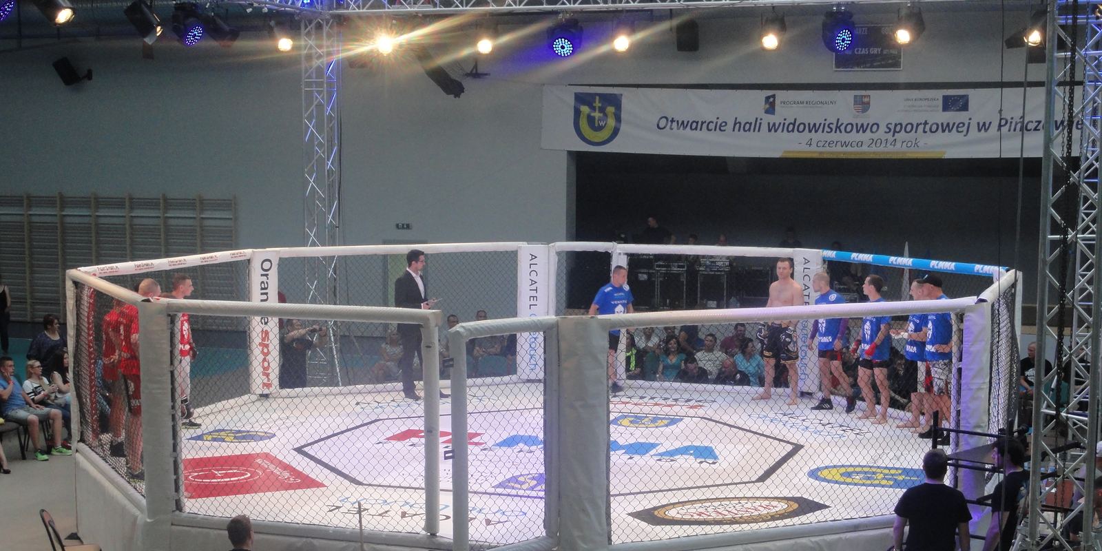 An empty eight-sided MMA cage under arena lights