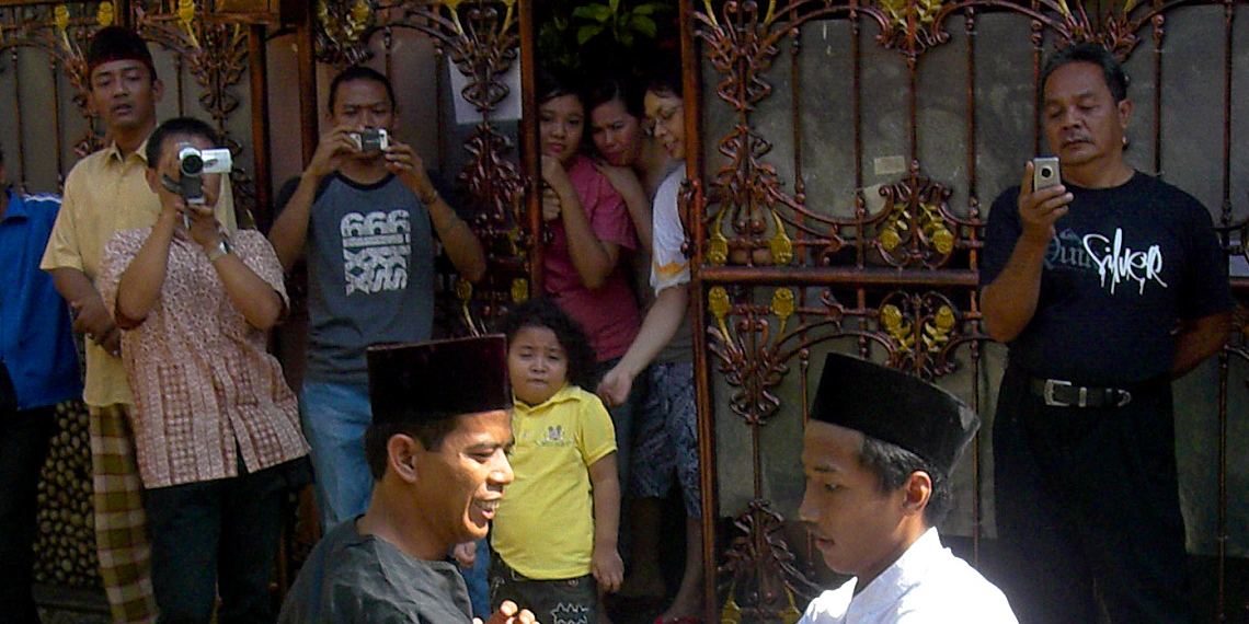 A pencak silat performer in traditional black clothing striking a pose